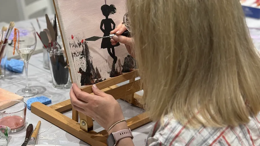 Woman painting silhouette on canvas in studio.