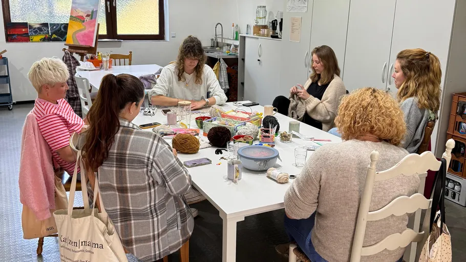Group knitting around a table in a workshop.