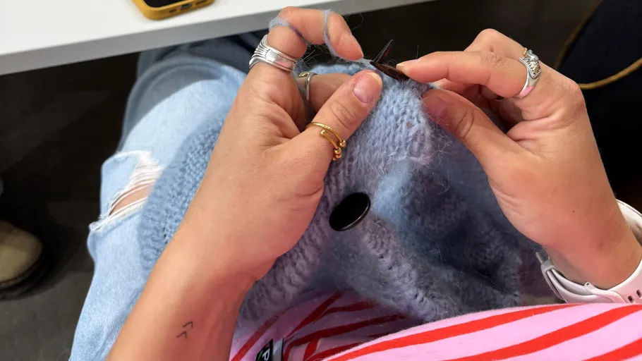 Person strickt blauen Stoff im Sitzen.