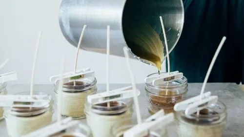Person pouring wax into glass candle jars.