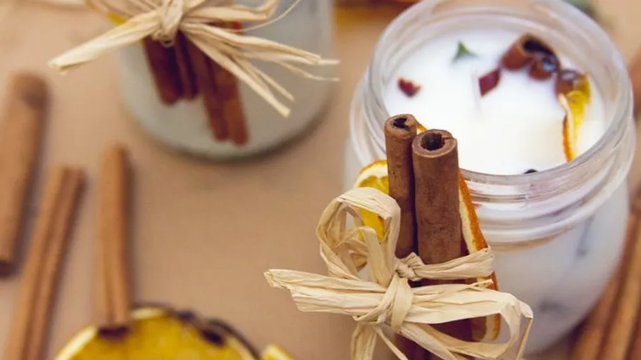 Candle in jar with cinnamon sticks tied.