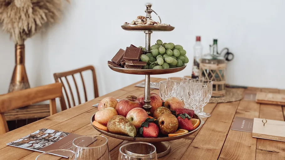 Tiered fruit stand with grapes and apples on table.