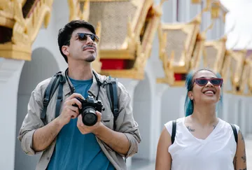 Two tourists with camera exploring temple.