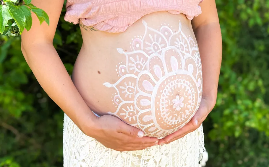 Schwangerenbauch mit Hennadesign im Freien.