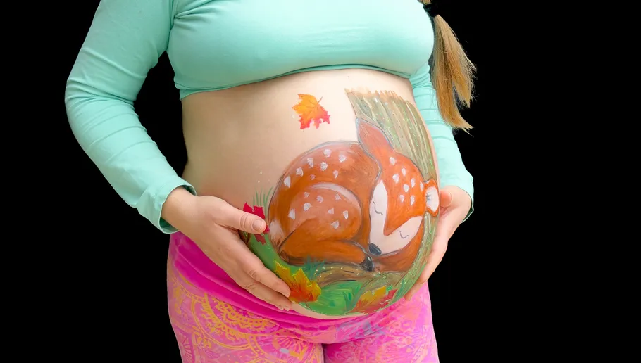 Schwangere Frau mit Reh auf Bauch gemalt.