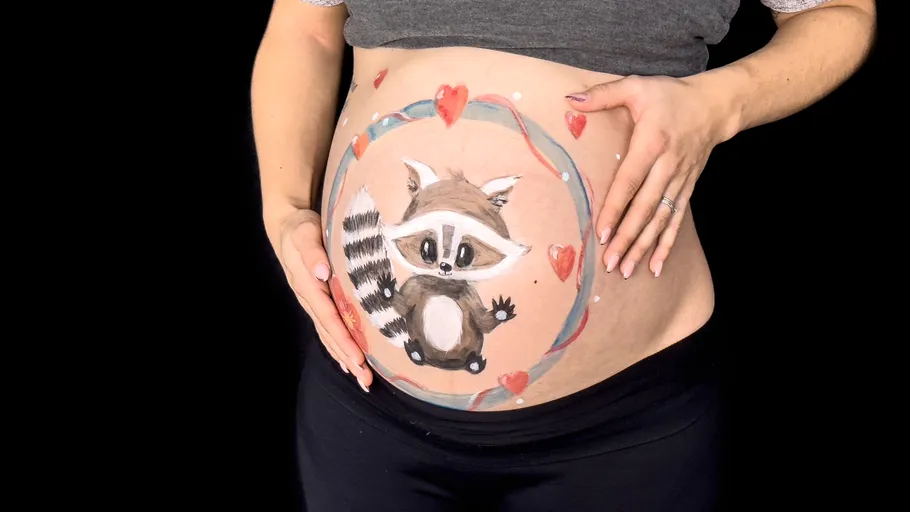 Schwangerenbauch mit Waschbärmotiv bemalt.