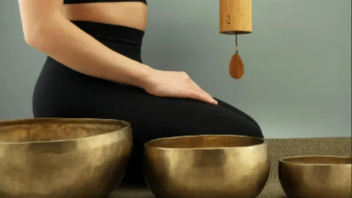 Person meditating with singing bowls indoors.