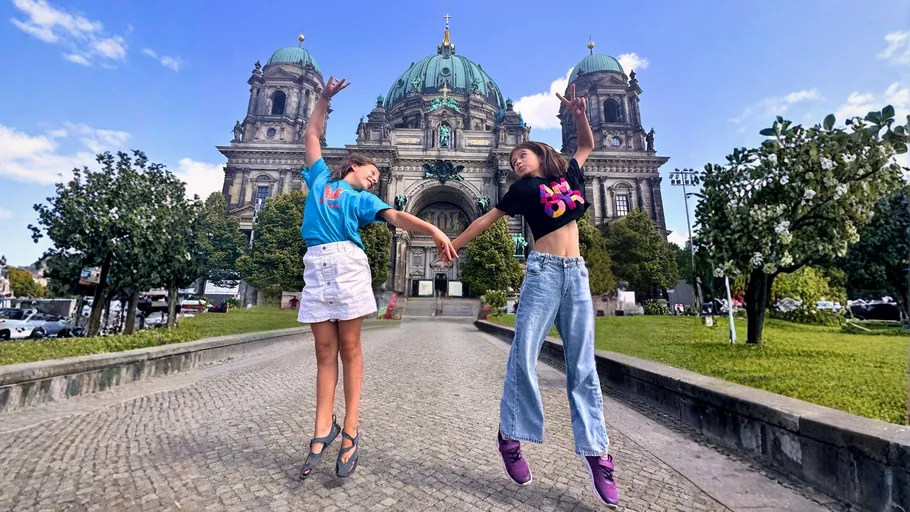 Two children jumping in front of cathedral.