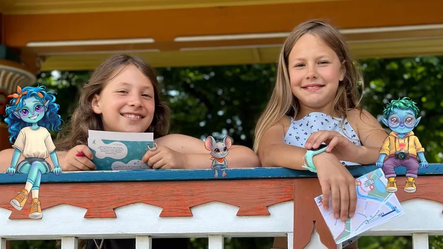 Zwei Mädchen lächeln mit Cartoon-Figuren auf Veranda.
