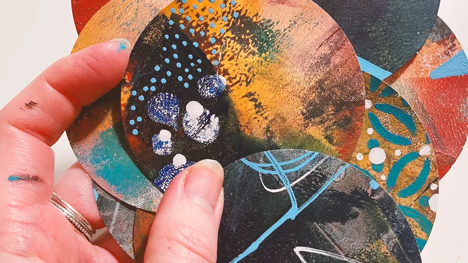 Hand hält bunte bemalte Kreise.