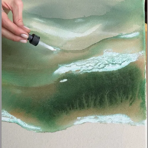 Hand applies liquid on green abstract painting.
