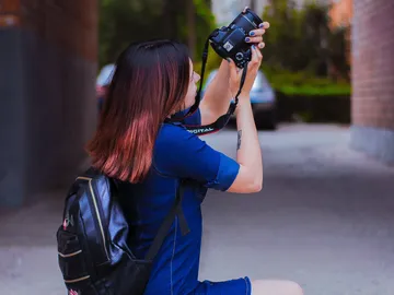 Frau fotografiert mit Kamera in einer schmalen Gasse.