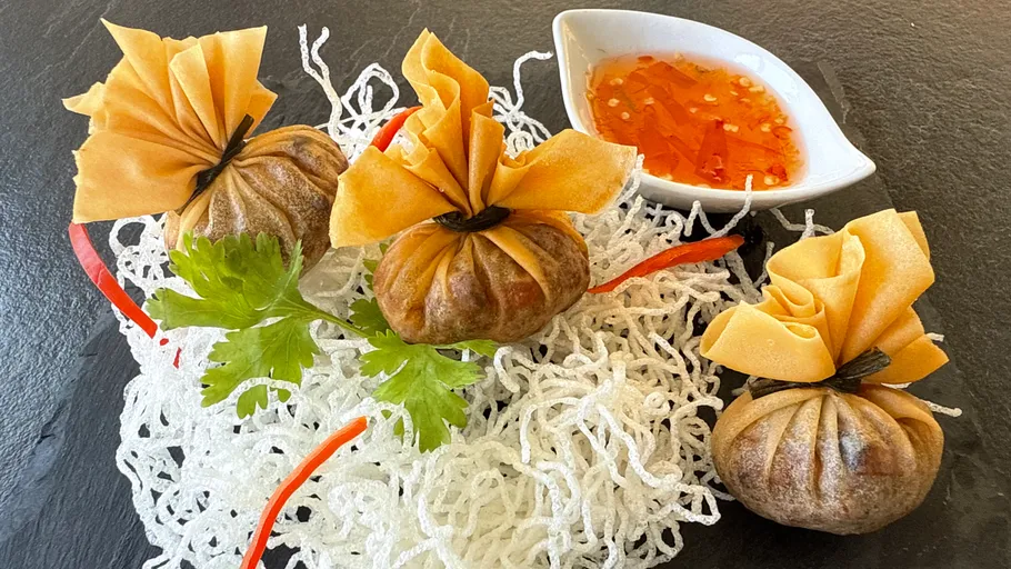 Frittierte Teigtaschen mit Sauce auf dekorativem Teller.