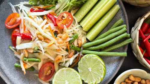 Bunter thailändischer Salat mit Limette auf grauem Teller.