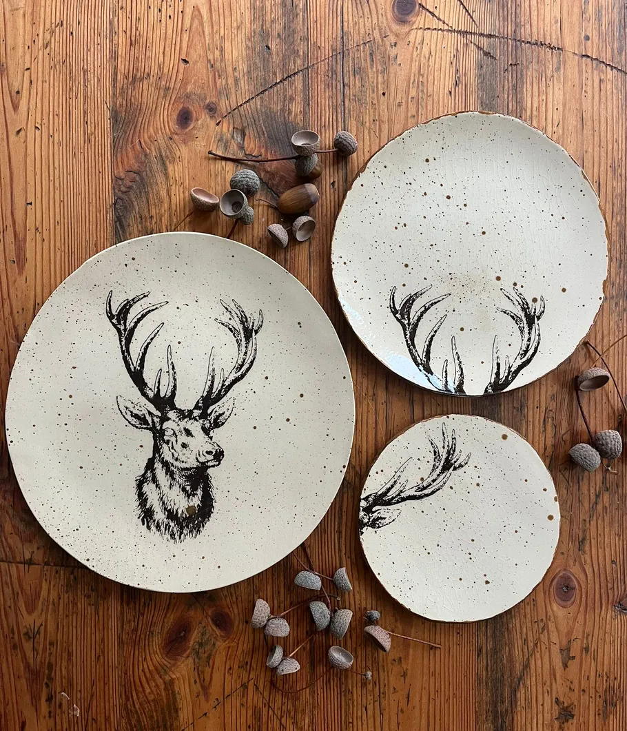 Ceramic deer plates on wooden table.
