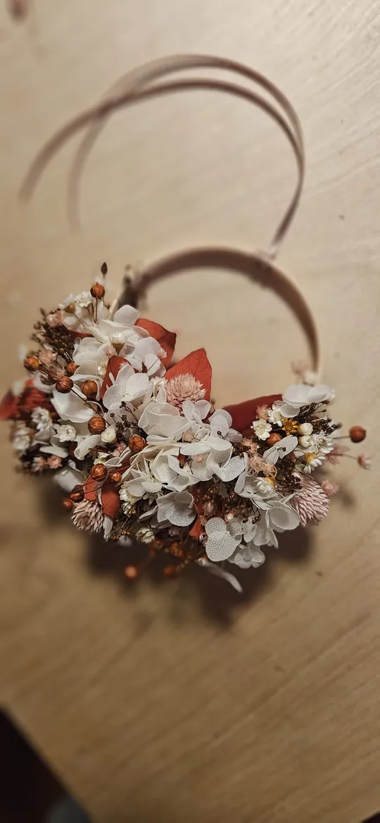 Blumenstirnband mit weiß-roten Blumen auf Holz.
