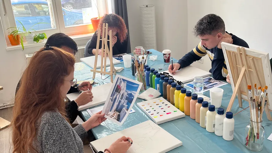 Group painting class indoors at a table.