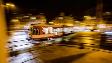 Straßenbahn fährt schnell nachts in Stadt.