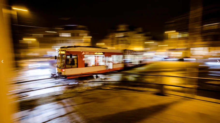 Tram moving quickly at night in city.