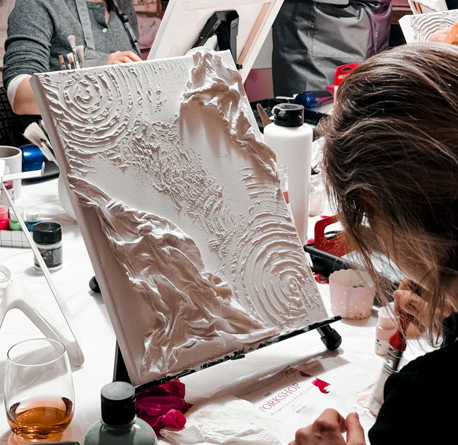 Person painting textured canvas in art studio.