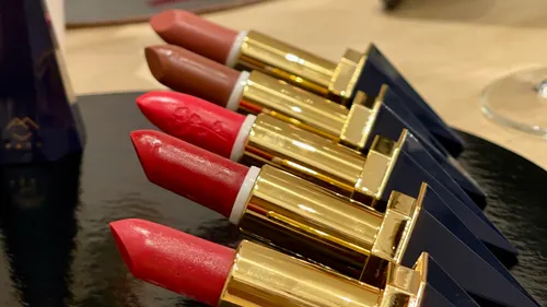 Five lipsticks arranged on black surface.