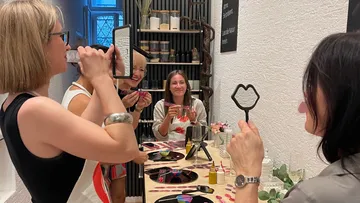 Frauen machen Fotos mit lippenförmigen Requisiten drinnen.