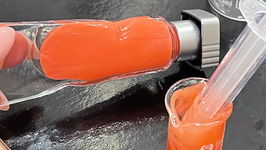 Orangene Flüssigkeit wird in ein Becherglas gegossen.