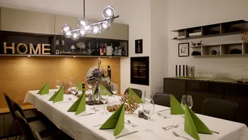 Elegant gedeckter Esstisch mit grünen Servietten.