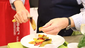 Koch schält geröstete Paprika auf Teller.