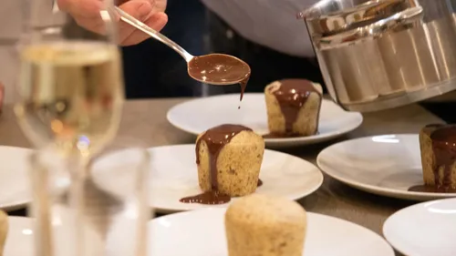 Chef pours chocolate on desserts, table setting.