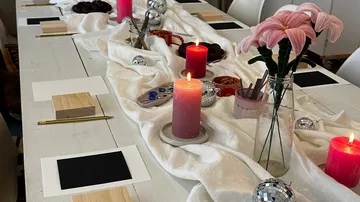 Geschmückter Tisch mit Kerzen und Blumen.