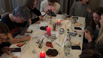 People crafting at a table with candles.