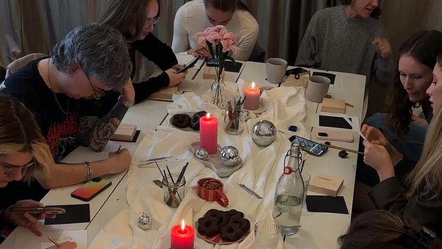 Menschen basteln an einem Tisch mit Kerzen.