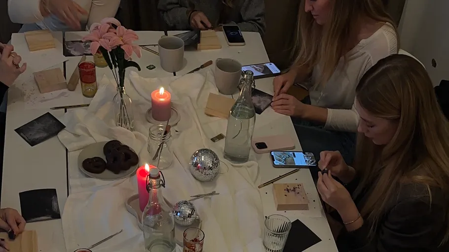People crafting at a table with candles.