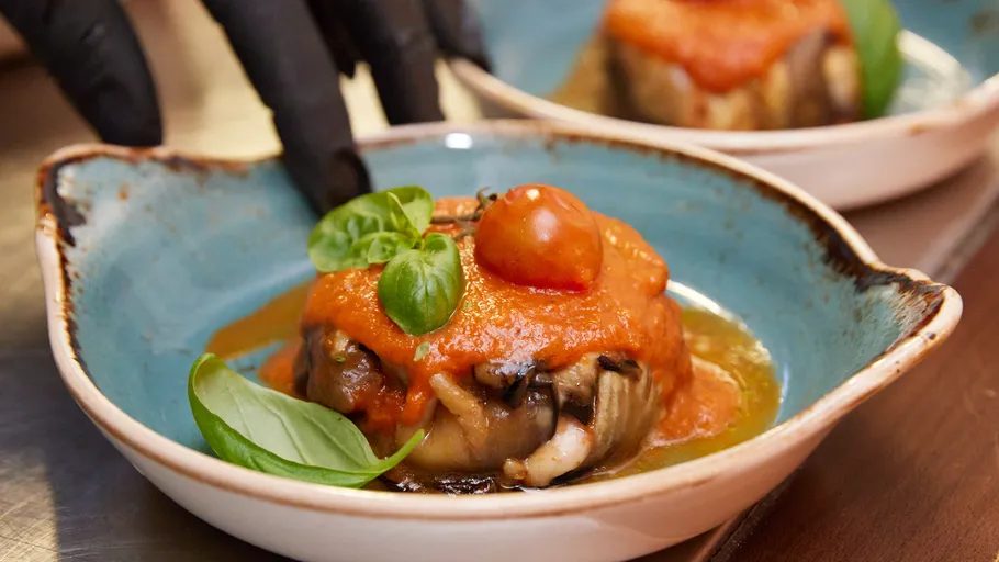 Stuffed eggplant with tomato sauce in bowl.