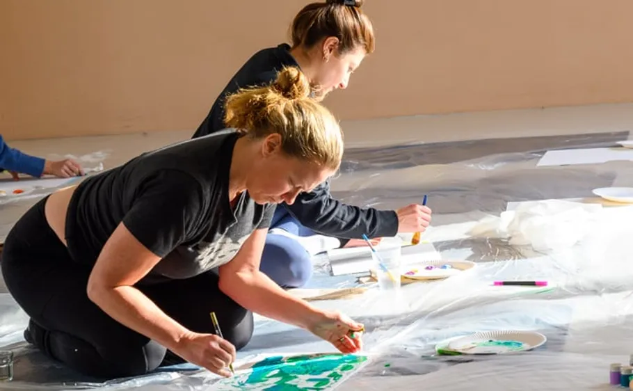 Two women painting on floor indoors.