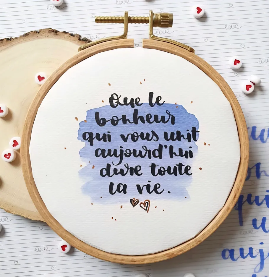 Embroidery hoop with French quote, decorative background.