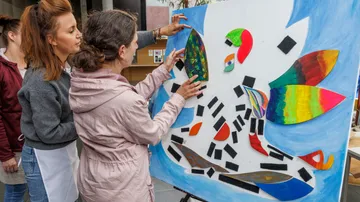 Frauen arrangieren bunte Stücke auf einem Brett.