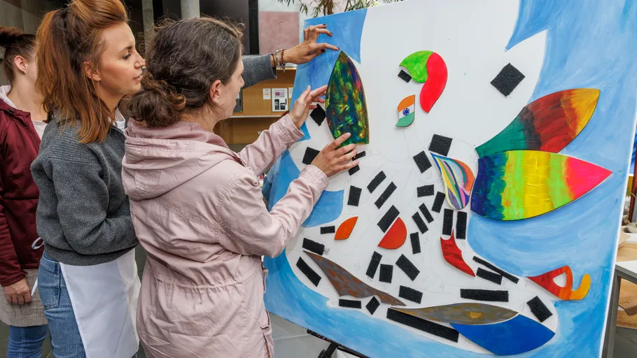 Women arranging colorful pieces on a board.