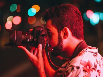 Fotograf hält Kamera, während er bei Nacht fotografiert.