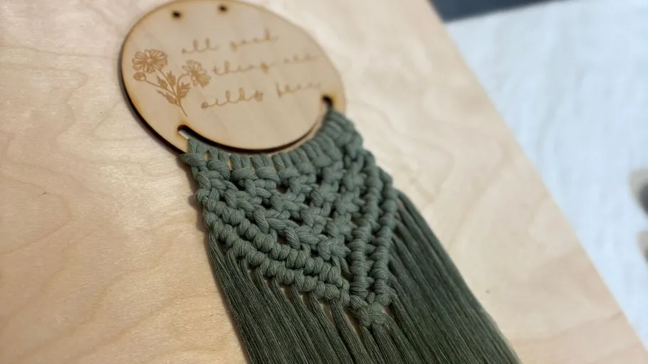 Macrame hanging on wooden surface.