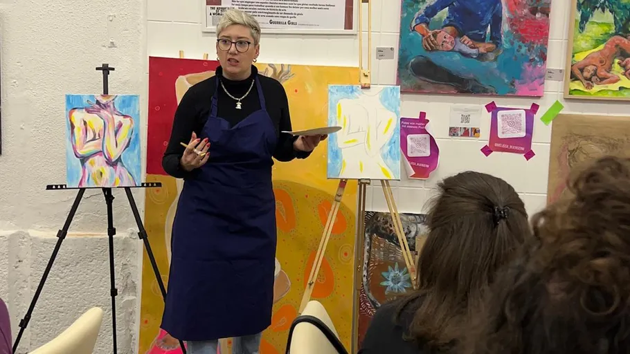 Artist presenting painted canvases in a studio.