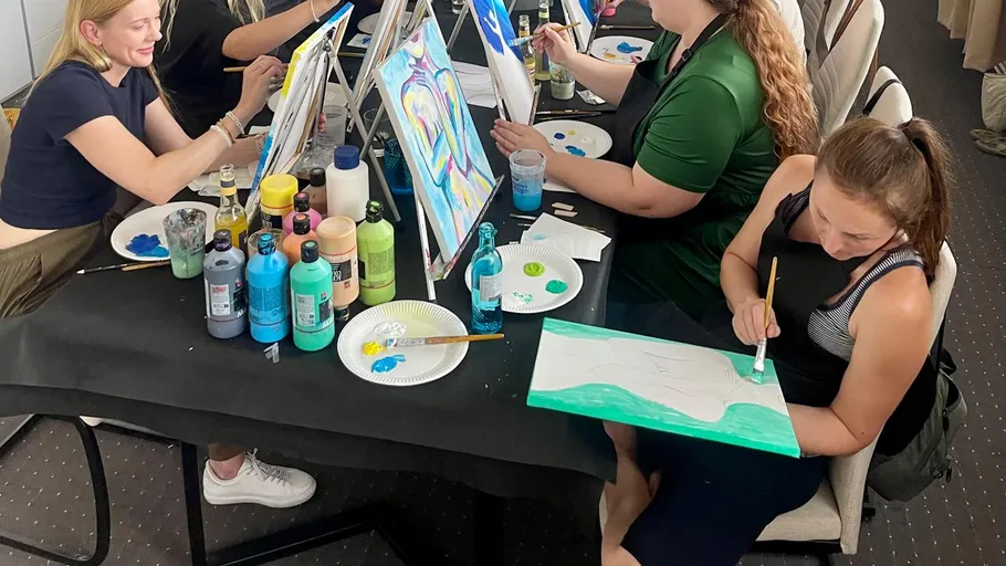 Frauen malen an einem Workshop-Tisch.