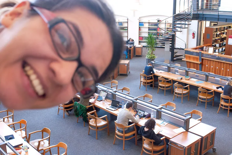 Smiling person photobombing a library study scene.