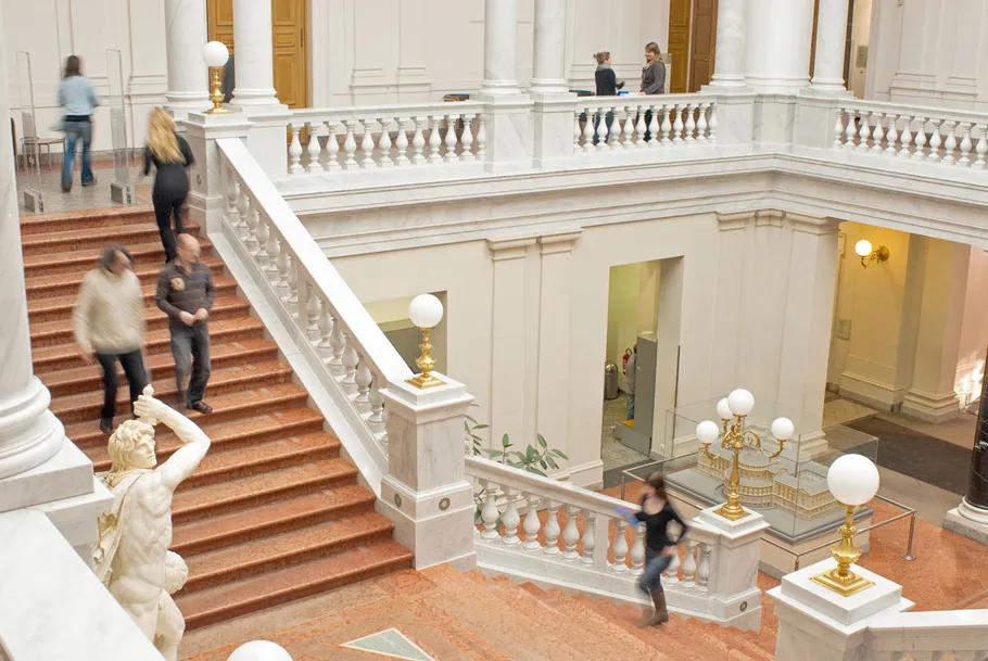 People walking in grand staircase, museum interior.