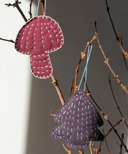 Stitched fabric ornaments hanging on branches.
