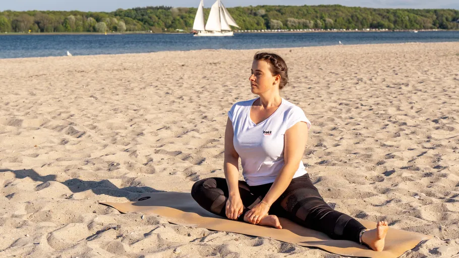 Woman doing yoga on a sandy beach.