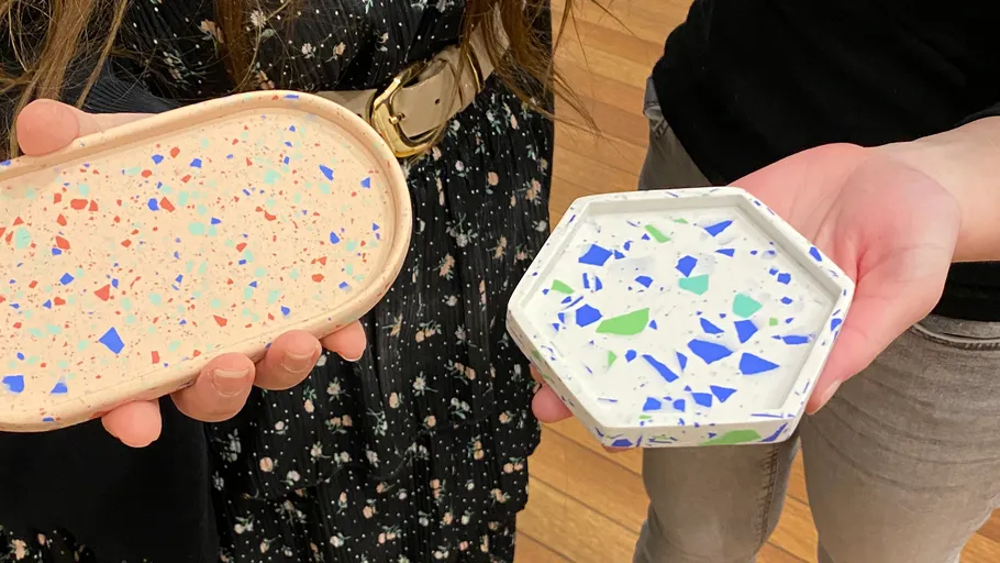 Two people holding colorful terrazzo trays.