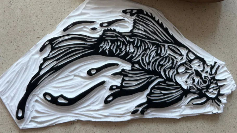 Fish linocut design on textured surface.