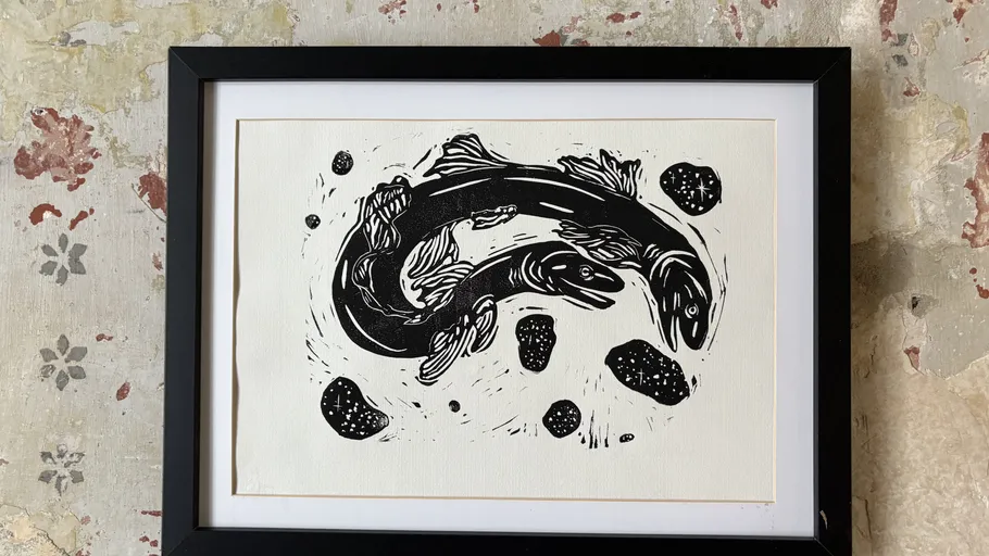 Framed fish artwork with textured wall background.